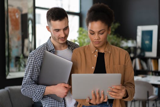 Two young adults collaborating with laptops in a stylish home office setting.